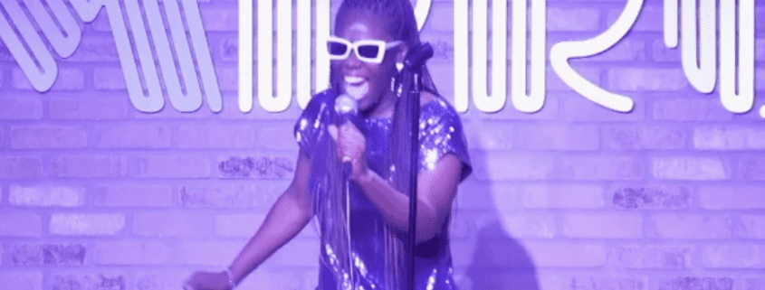 Comedian performing on stage with microphone.